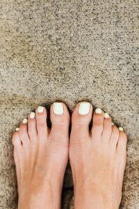 Well-maintained toenails on a carpet, evoking the appearance of healthy feet post-toenail fungus treatment in Indianapolis.