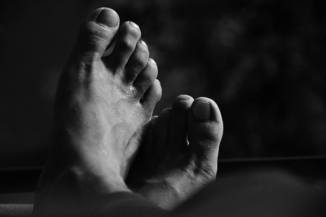 A black and white image of feet with a focus on the toenails.